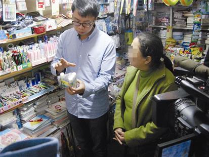 图为：市场抽查人员在小学附近的商店购买固体胶